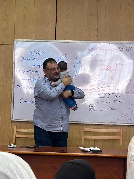 الأستاذ يشرح وعلى كتفه الطفل