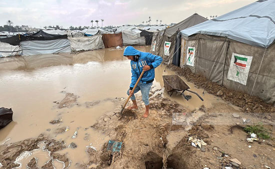 فلسطينى يحاول عمل سد لمنع تدفق المياه الى الخيام