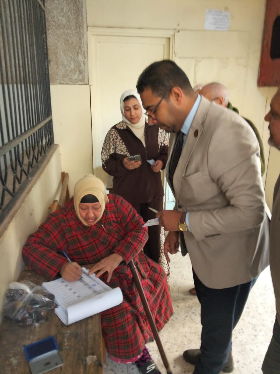 قاضى يساعد سيدة مسنة للإدلاء بصوتها قاضى يساعد سيدة مسنة للإدلاء بصوتها