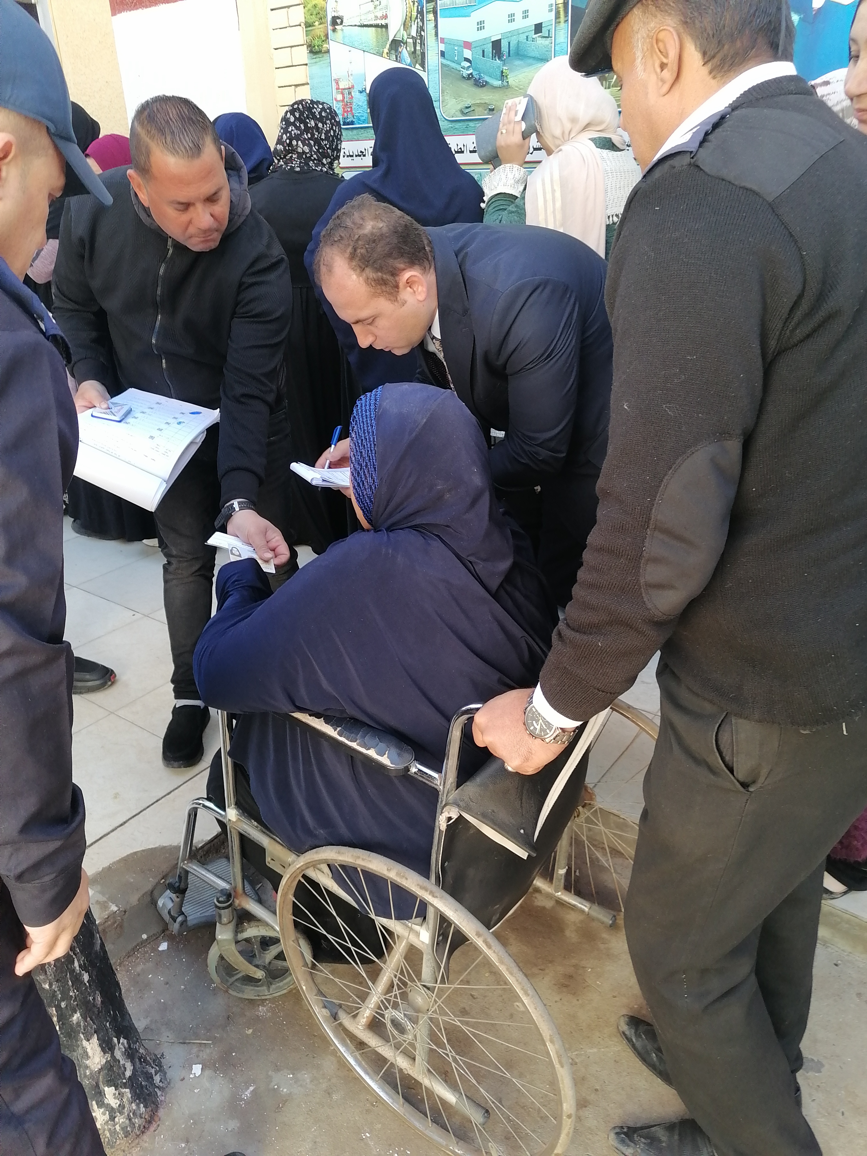 رئيس لجنة يخرج لمساعدة سيدة من كبار السن للإدلاء بصوتها رئيس لجنة يخرج لمساعدة سيدة من كبار السن للإدلاء بصوتها