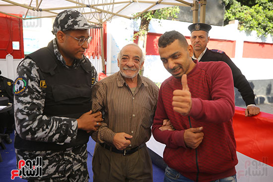 شرطي يساعد مسن أثناء العملية الأنتخابية شرطي يساعد مسن أثناء العملية الأنتخابية