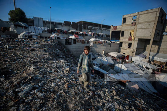 طفل فلسطينى نازح يسير وسط النقايات