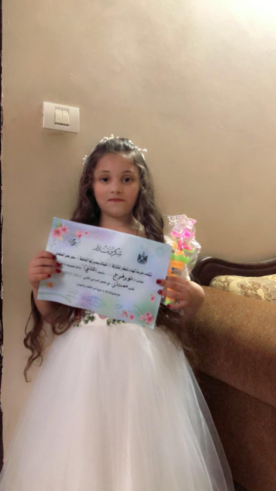 نور فرج تحمل شهادة تقرير من مدرستها