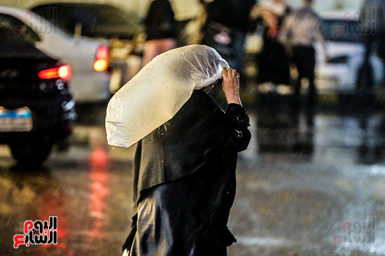 سيدة تغطى رأسها أثناء المطر سيدة تغطى رأسها أثناء المطر