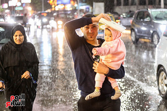 رجل يحمى طفله من سقوط المطر رجل يحمى طفله من سقوط المطر