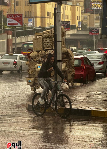 مواطن يعبر الطريق بدراجته تحت المطر مواطن يعبر الطريق بدراجته تحت المطر
