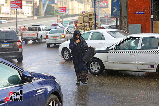 سيدة تعبر الشارع تحت الأمطار سيدة تعبر الشارع تحت الأمطار