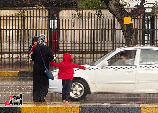 طفل يصطحب أمه لعبور الطريق تحت المطر طفل يصطحب أمه لعبور الطريق تحت المطر