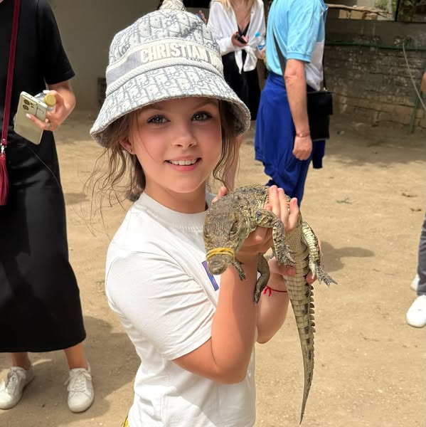 طفلة أجنبية تلهو مع تمساح صغير بجزيرة الموز