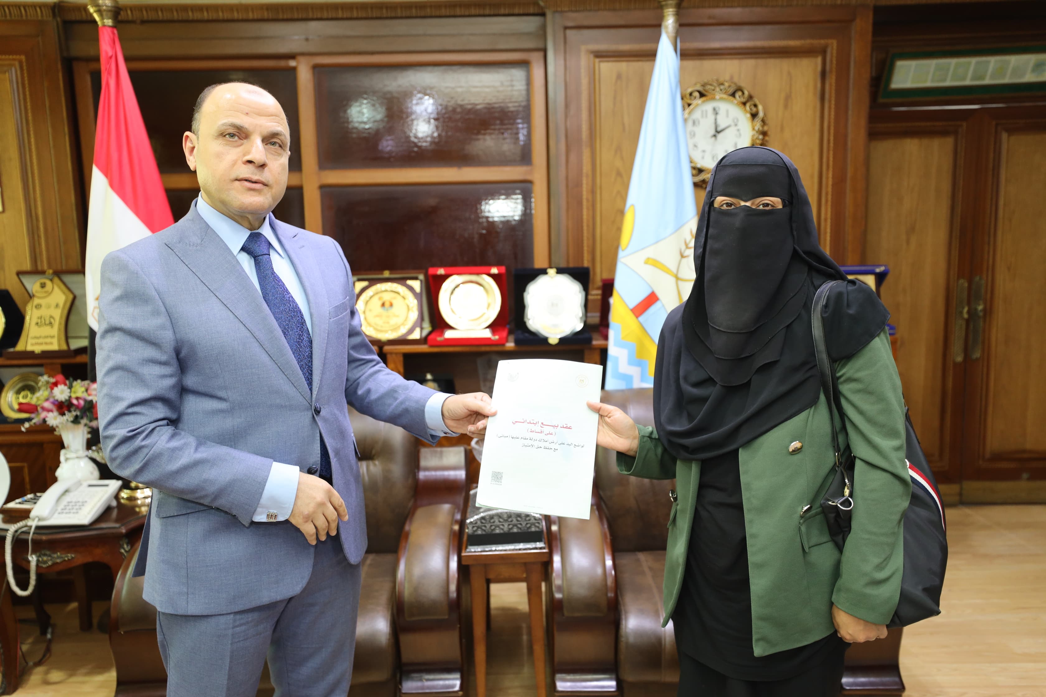 سيدة تتسلم عقد تقنين سيدة تتسلم عقد تقنين