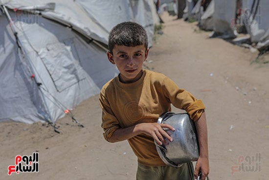 طفل فلسطيني نازح داخليًا ينتظر استلام حصة طعام من مطبخ خيري طفل فلسطيني نازح داخليًا ينتظر استلام حصة طعام من مطبخ خيري