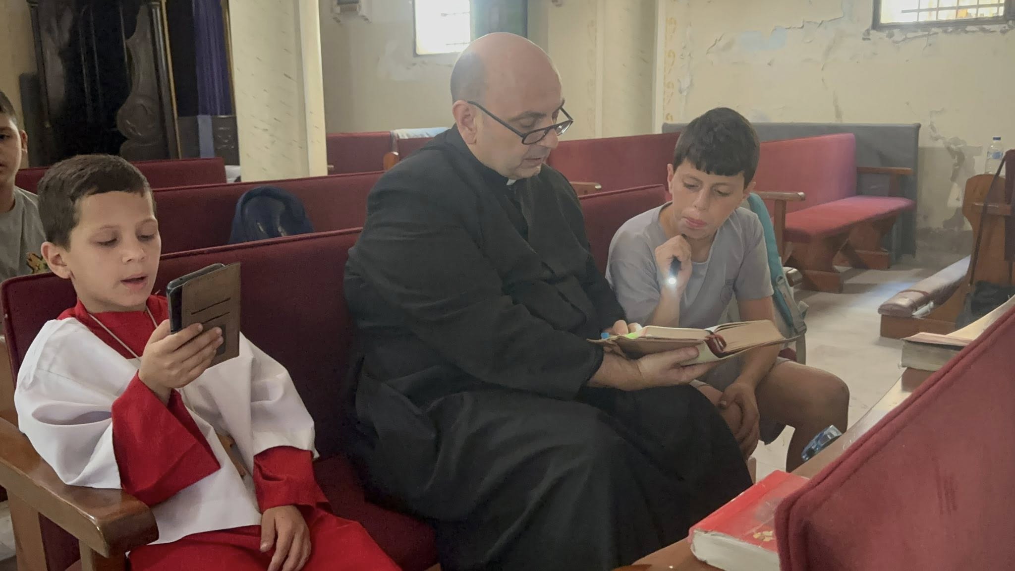 الأب جابرييل رومانيلى راعى الكنيسة مع الأطفال يعلمهم أيات من الكتاب المقدس