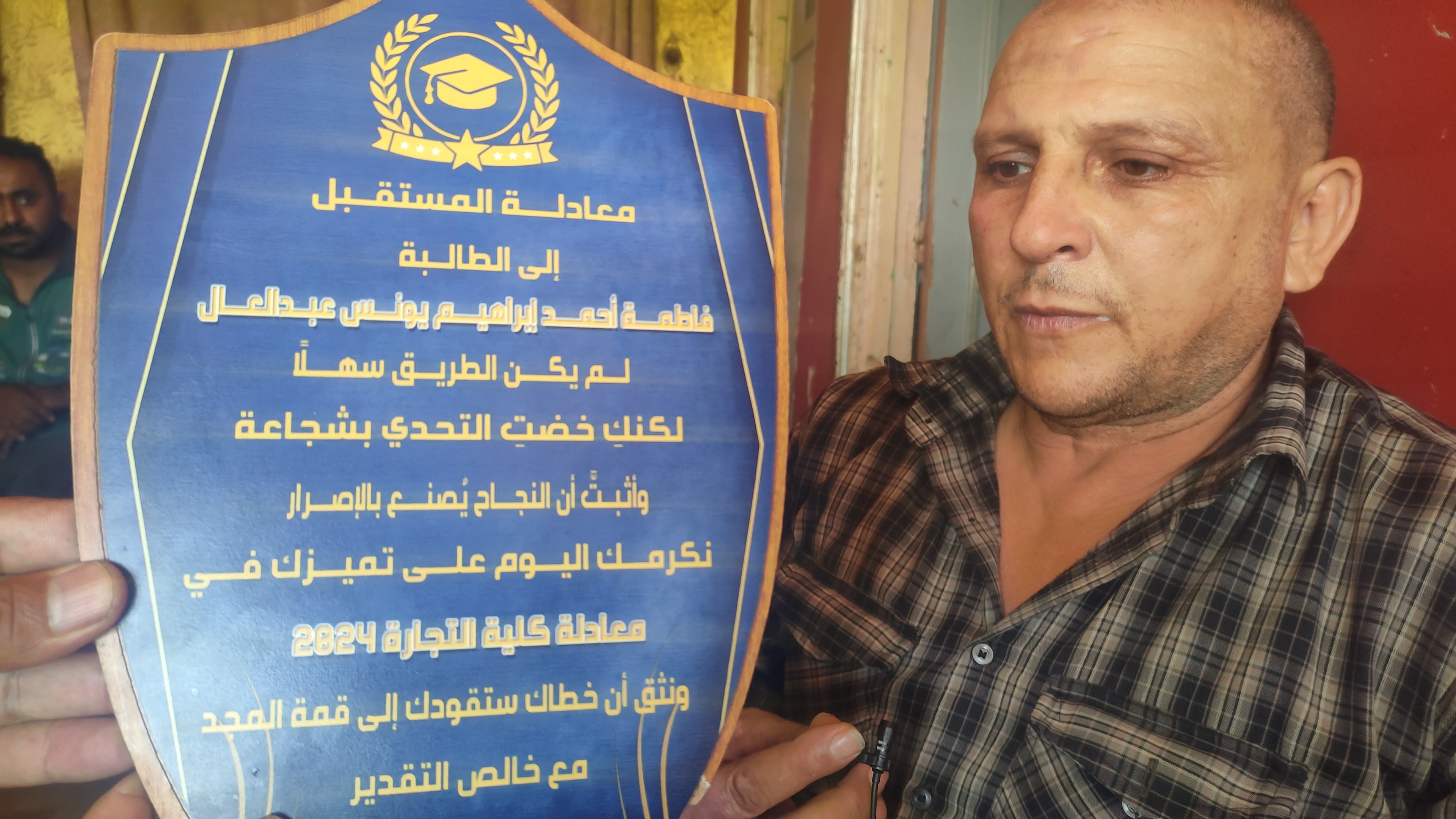 الاب يحمل درع تكريم نجلته المتوفية