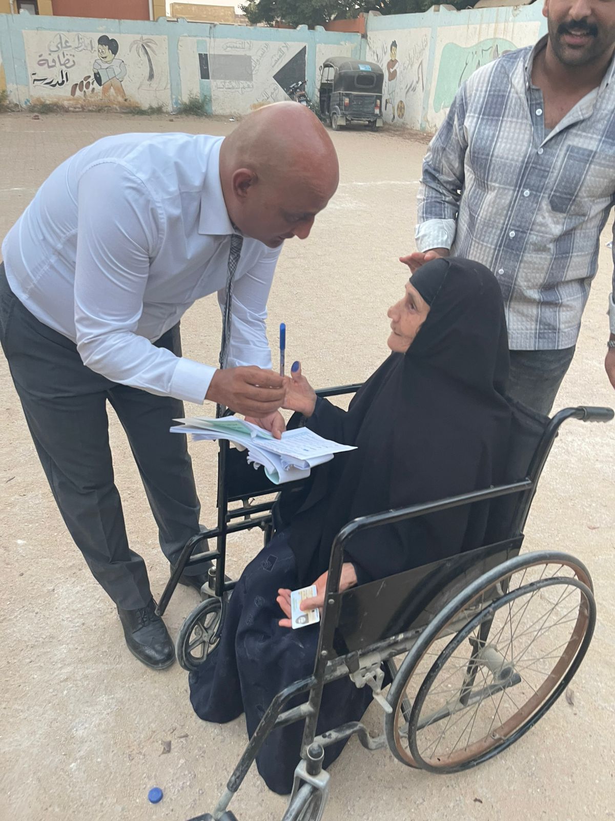 رئيس لجنة بالفيوم يتوجه إلى مسنة خارج اللجنة لمساعدتها على الإدلاء بصوتها رئيس لجنة بالفيوم يتوجه إلى مسنة خارج اللجنة لمساعدتها على الإدلاء بصوتها