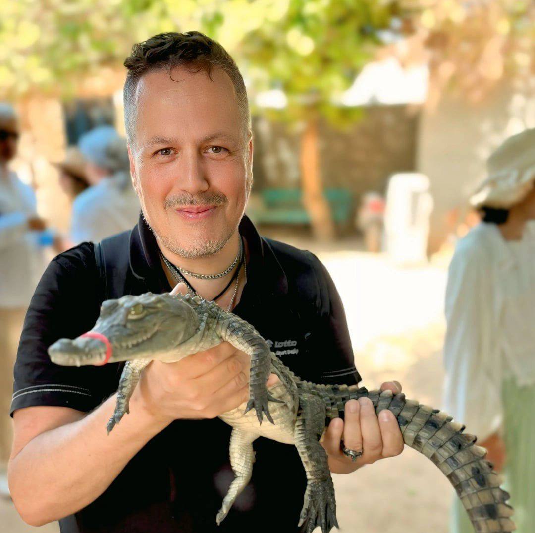 متعة أحد السائحين مع تمساح صغير بجزيرة الموز