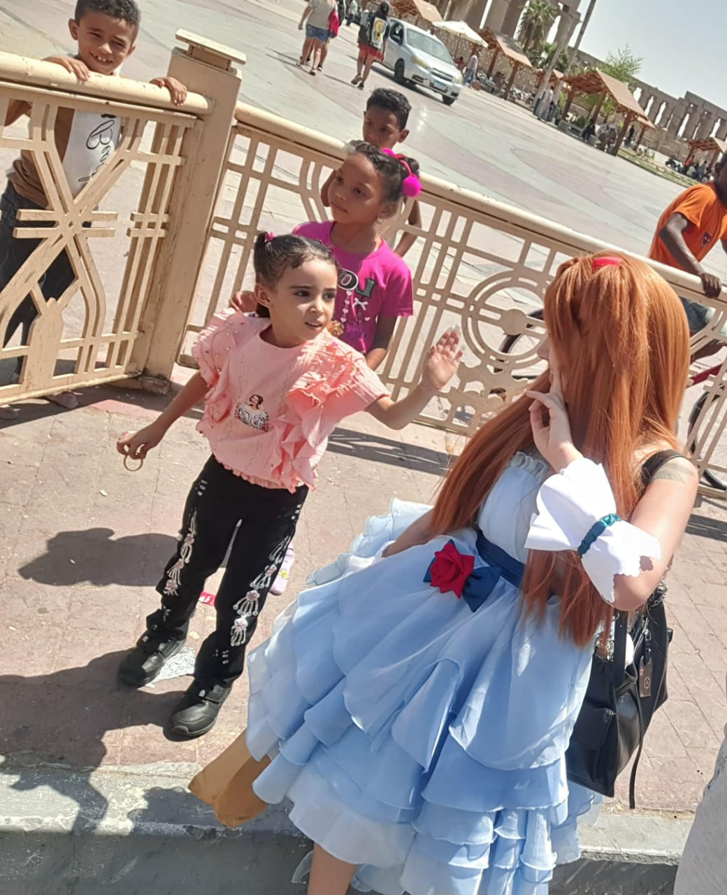 صينية تستمتع مع أطفال الأقصر في ساحة أبوالحجاج بزي باربي الكرتونى