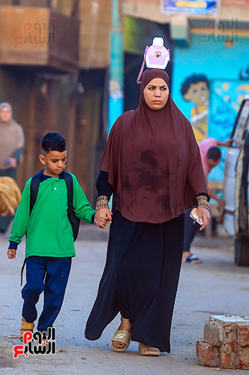 سيدة تقوم بتوصيل ابنها الي المدرسة