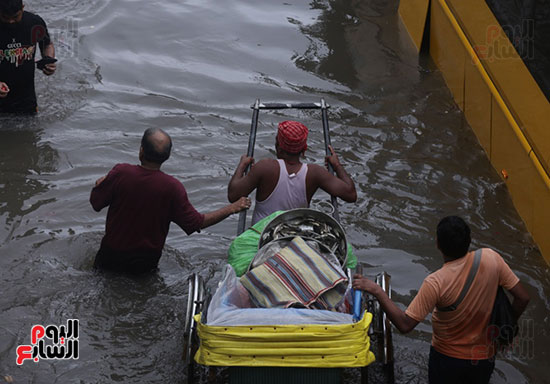مواطنين هنوداً يقفون وسط مياه الأمطار الغزيرة في الشوارع