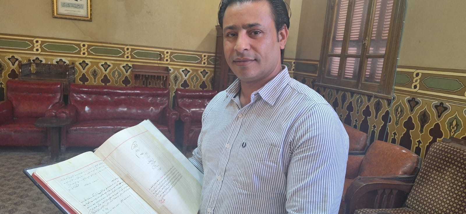 مراسل اليوم السابع ممسكا بدفتر المعهد الأثري