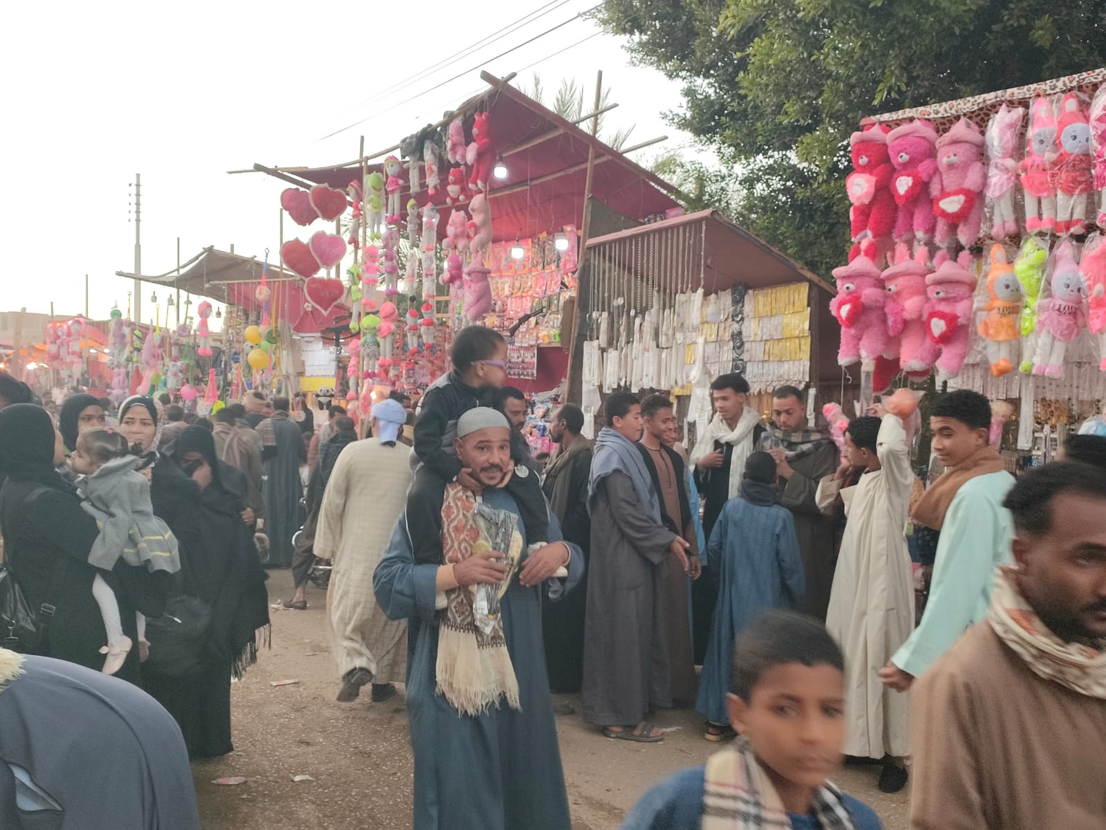 أب يحمل إبنه فى احتفالات المولد بقرية الدير