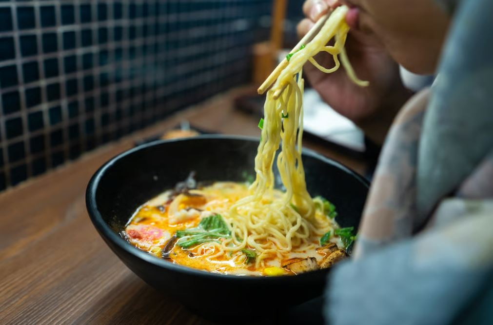 امرأة تتناول طبقًا من نودلز الرامين في مطعم ياباني