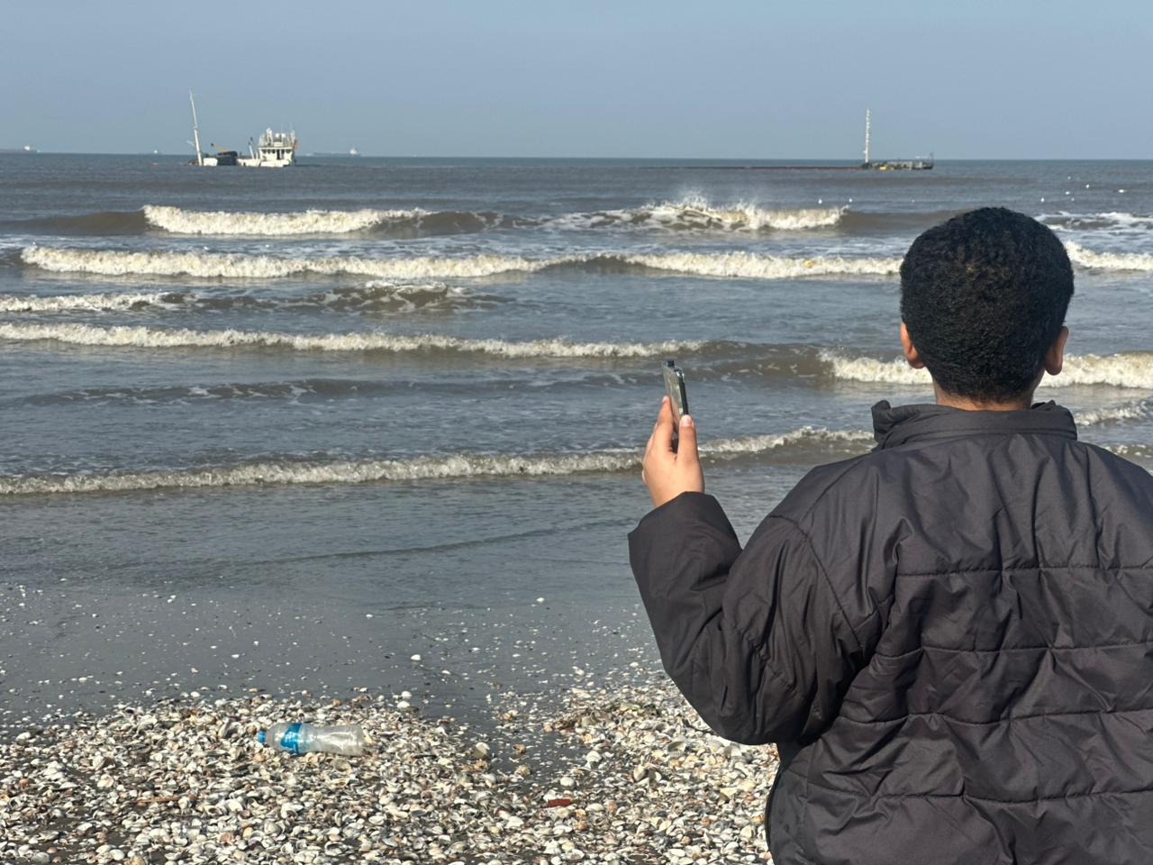 طفل يلتقط صور امام السفينة