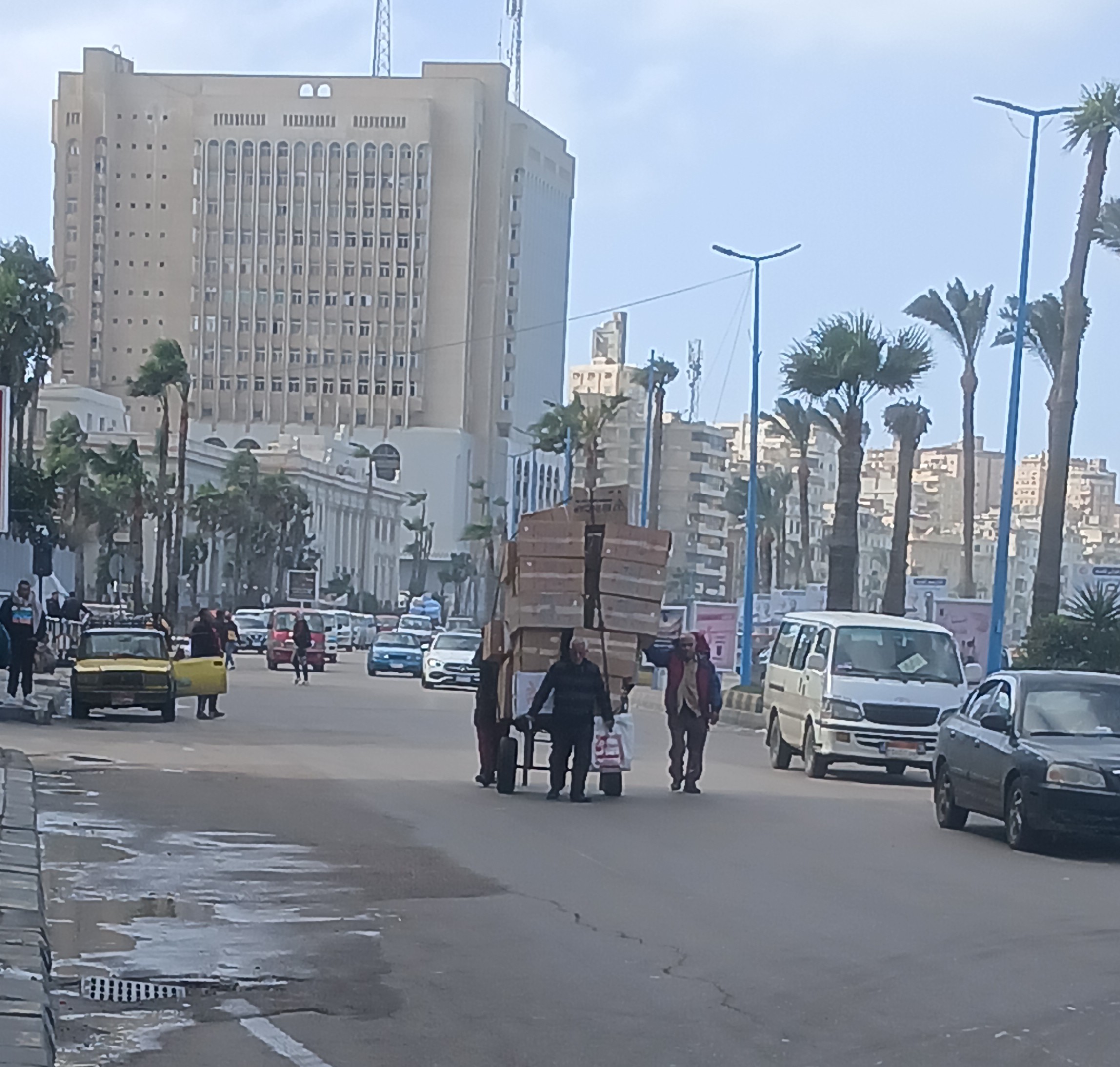 عامل يحمل عربة محملة بضائع تحت الظروف الجوية الإسكندرية