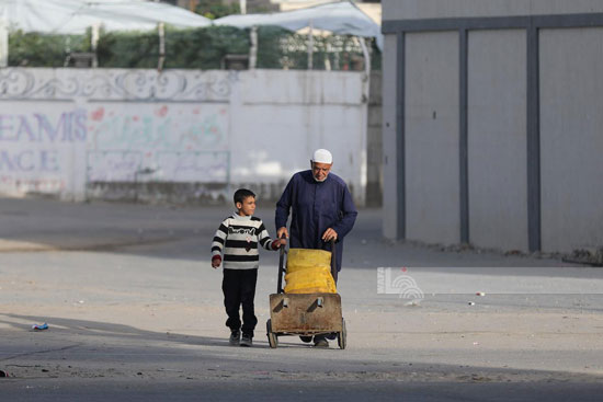 مسن فلسطينى نازح يصطحب طفل للحصول على المياه مسن فلسطينى نازح يصطحب طفل للحصول على المياه