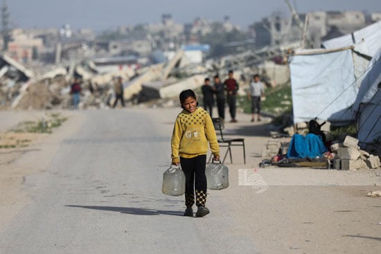 طفلة تحمل قوارير المياه