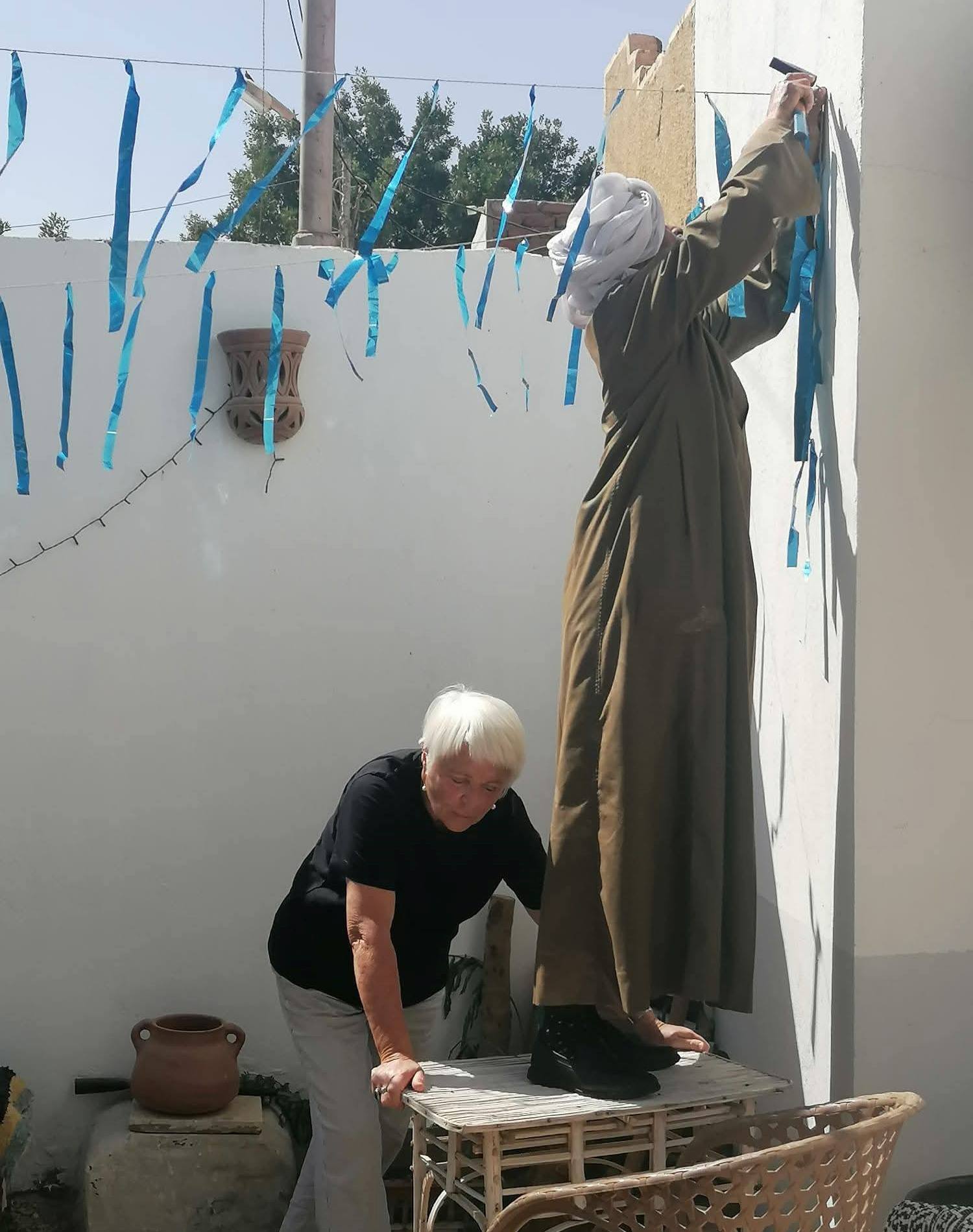 عامل يساعد السائحة البلجيكية فى تعليق زينة رمضان