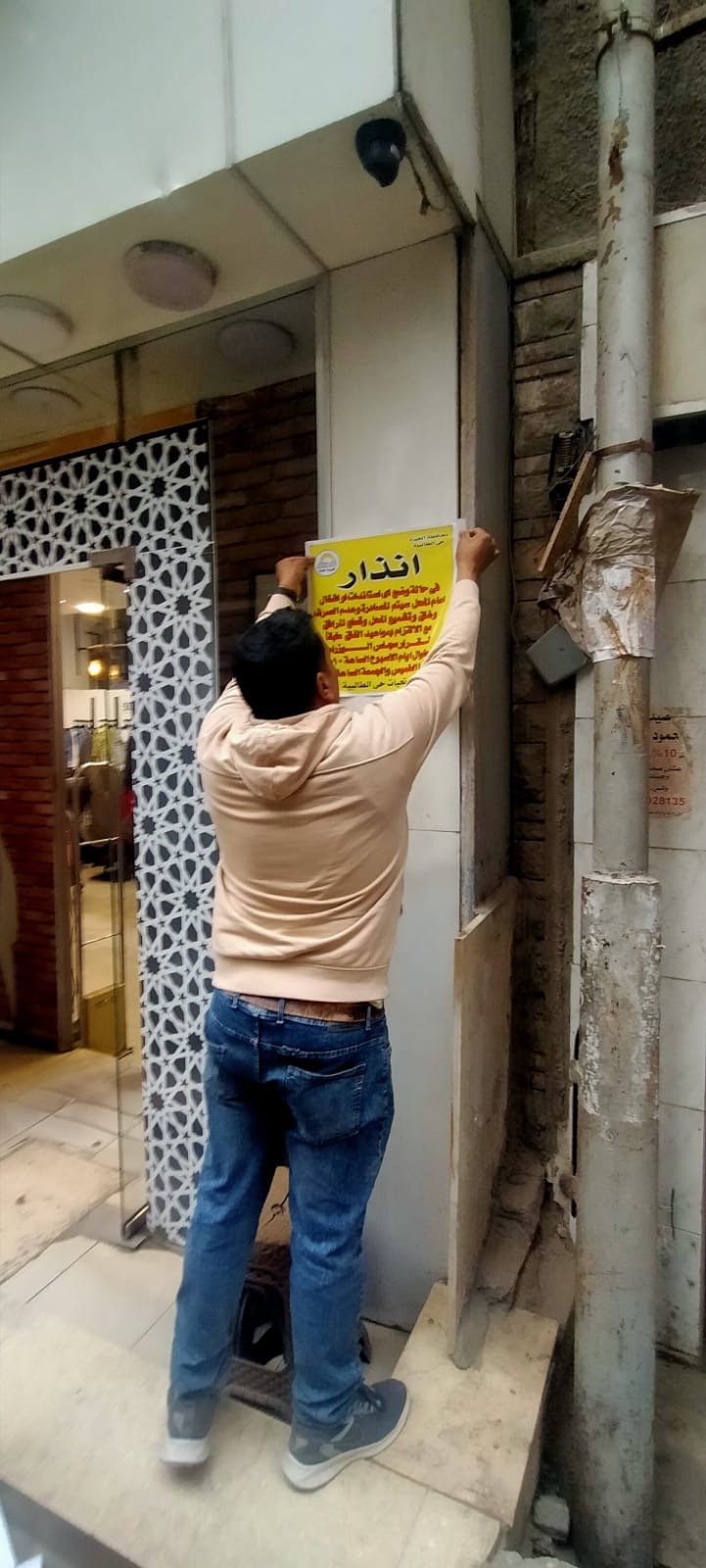 تعليق بنرات تحذيرية على المحال في حي الطالبية