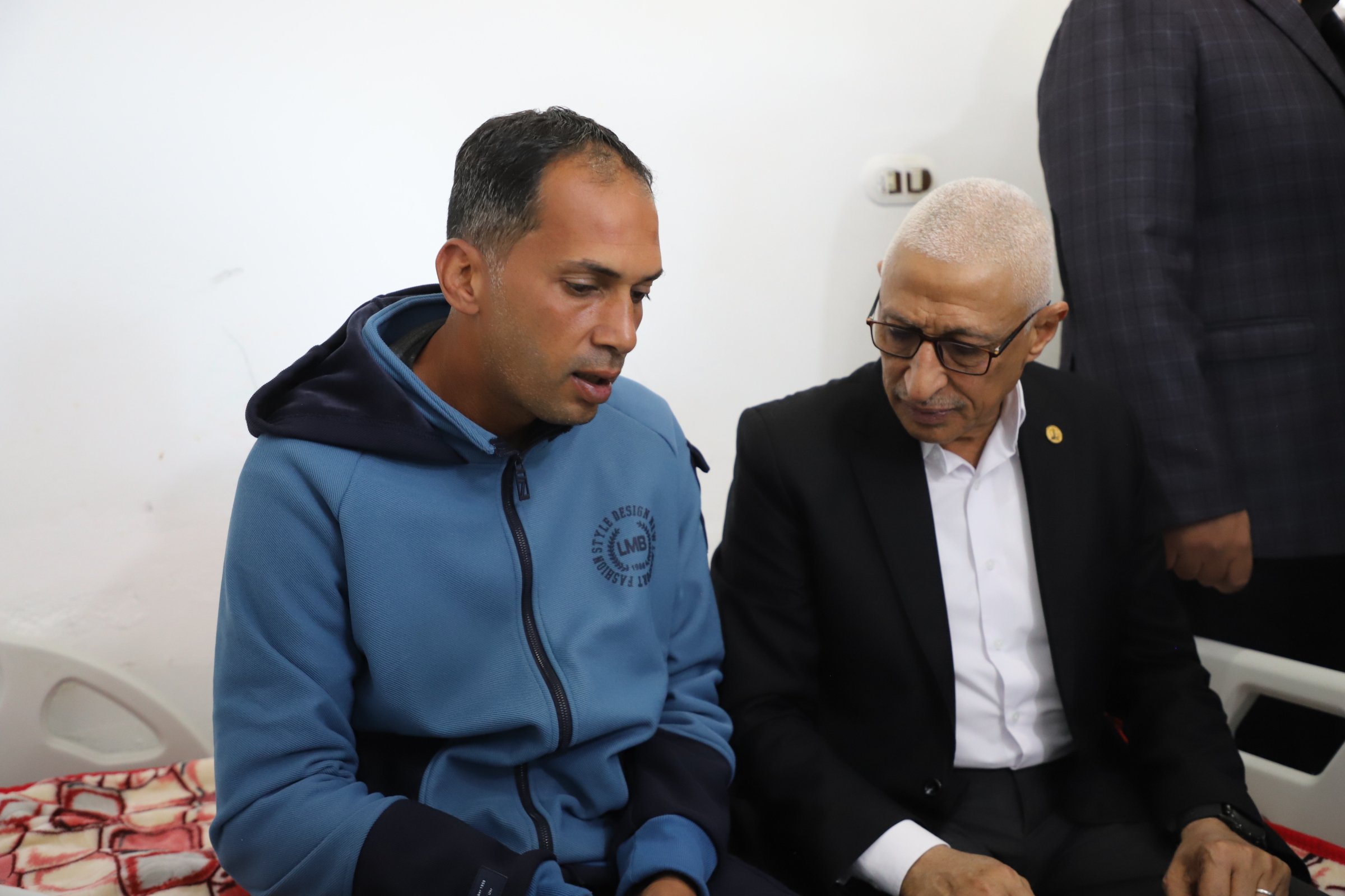 محافظ شمال سيناء يجلس مع مصاب فلسطيني يتلقي العلاج 