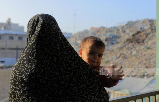 أم تحمل طفل وسط القمامة