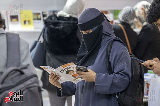 سيدة تتفقد القصص والكتب داخل المعرض
