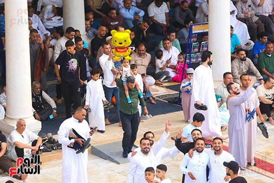 الاب يحمل الطفله على كتفه قبل صلاه العيد