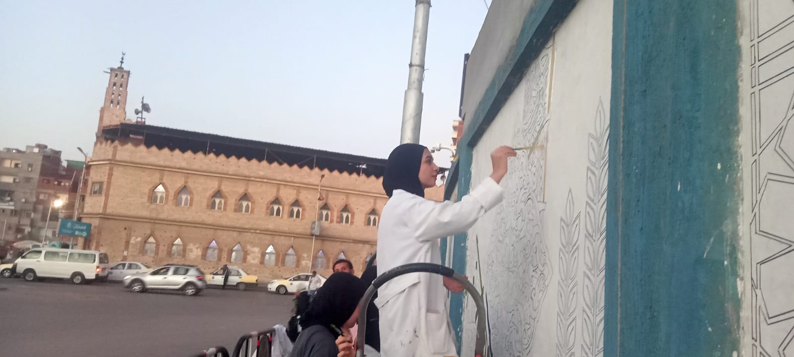 مشاركة طالبة في رسم جدارية