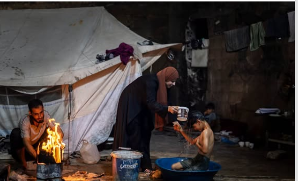 أم فلسطينية تدلى الماء على طفلها داخل خيمة النزوح