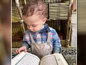 الطفل يحي أثناء تقليبه بصفحات المصحف بالمسجد النبوي