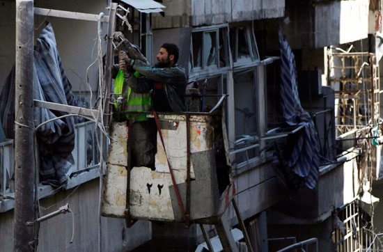 أشخاص يحاولون إصلاح خطوط الكهرباء بعد تضررها من سقوط براميل متفجرة على مدينة حلب السورية