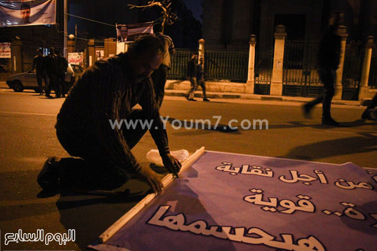أحد العمال يستعد لتعليق لافتة دعائية لمرشح نقابة الصحفيين