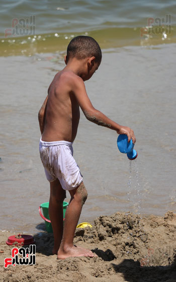 طفل يقوم بسقاية بيت من الرمال