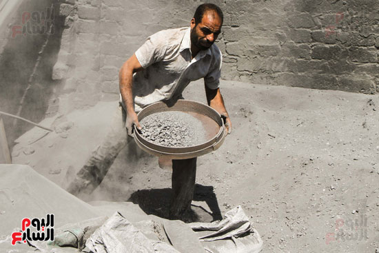 أحد العمال ينخل قطع الألومنيوم من الرماد