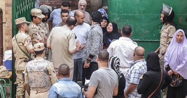 رجال الشرطة يساعدون سيدة مسنة للدخول للجان التصويت بمدرسة الشيخ زايد