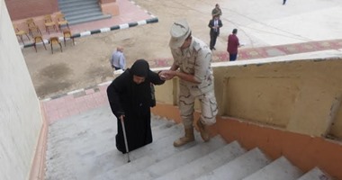 جندى بالقوات المسلحة يساعد سيدة مسنة فى دخول لجنة انتخابية بسوهاج