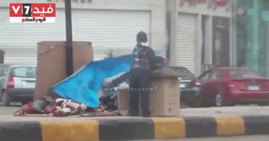 بالفيديو..مشهد مؤلم.. طفل يغطى والدته على الرصيف بمشمع لحمايتها من الأمطار