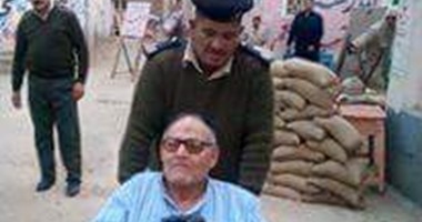 بالصور.. الأمن يساعد "مسن" على الإدلاء بصوته بالانتخابات فى الشرقية