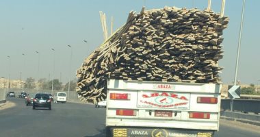 قارئ يرصد سيارة نصف نقل بحمولة زائدة من الأخشاب تسير أعلى الطريق الدائرى