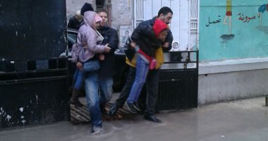 بالصور.. أولياء الأمور بالإسكندرية يحملون أبنائهم لدخول المدارس بسبب غرقها بالأمطار 