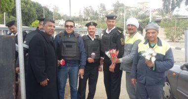 صور.. عمال نظافة الجيزة يوزعون الورود على ضباط الشرطة
