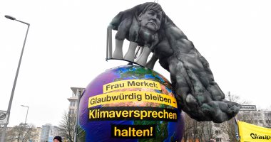 صور.. أعضاء منظمة السلام الأخضر ببرلين يتظاهرون بصورة لميركل ملطخة بالضباب الدخانى